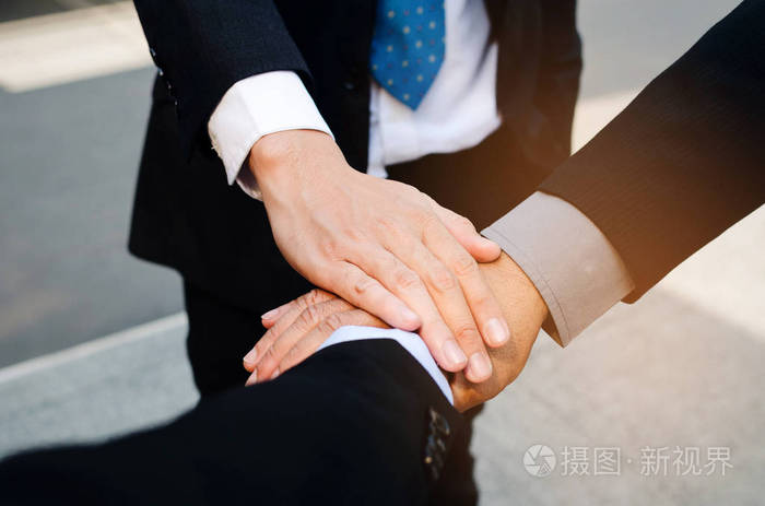 握手商务集团三人团队携手在城市与黑色公文包背景成功支持会议伙伴