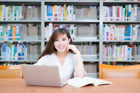 亚洲女孩在学校图书馆的笔记本电脑