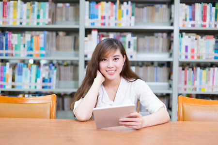 亚洲女孩在学校图书馆的平板电脑