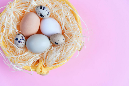 复活节彩蛋的不同颜色和鹌鹑蛋在一个柳条篮子的粉红色背景, 顶部视图, 平躺。复活节概念
