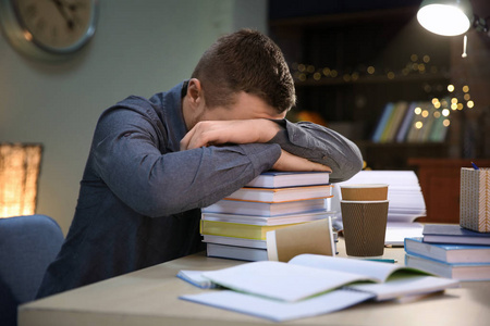 疲惫的学生睡在桌上的书堆在室内