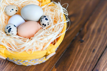 复活节彩蛋的不同颜色和鹌鹑蛋在一个柳条篮的木质背景。顶部视图。复活节的概念。特写