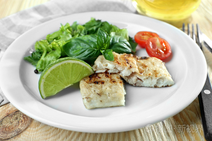 鱼排配沙拉和石灰在桌上的菜关闭