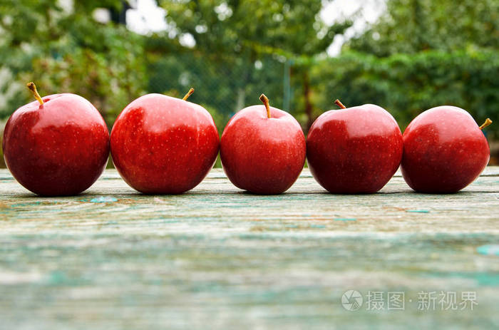 五个红苹果木绿色棕色岁的纹理表面上关闭苹果上模糊的自然背景