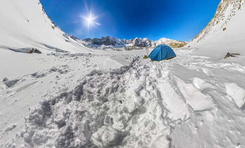 在山的雪峰的蓝色帐篷。广角全景