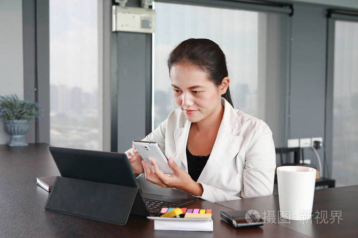 年轻的商人坐在椅子上在办公室使用智能手机的工作场所