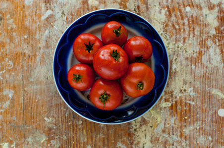 新鲜红番茄上蓝色的盘子上木桌背景