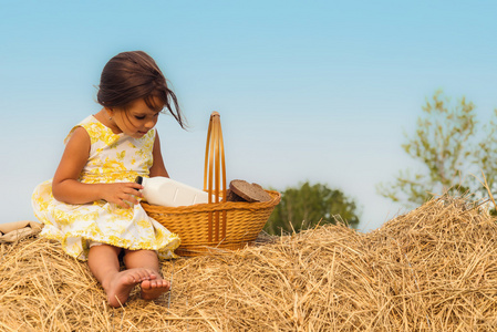 小女孩坐在干草堆里提着一个篮子健康食品