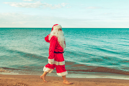 圣诞老人带了一袋礼物在海滩上。基督教的象征