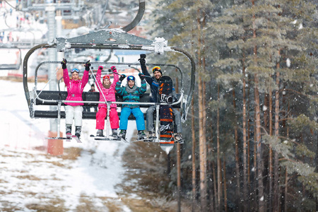 父母与男孩和女孩在椅子推力攀登在滑雪