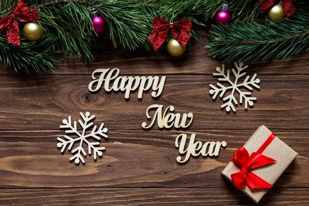 新年快乐与两个美丽的雪花和一个礼品盒的中心的木背景松树树枝上的屏幕顶部