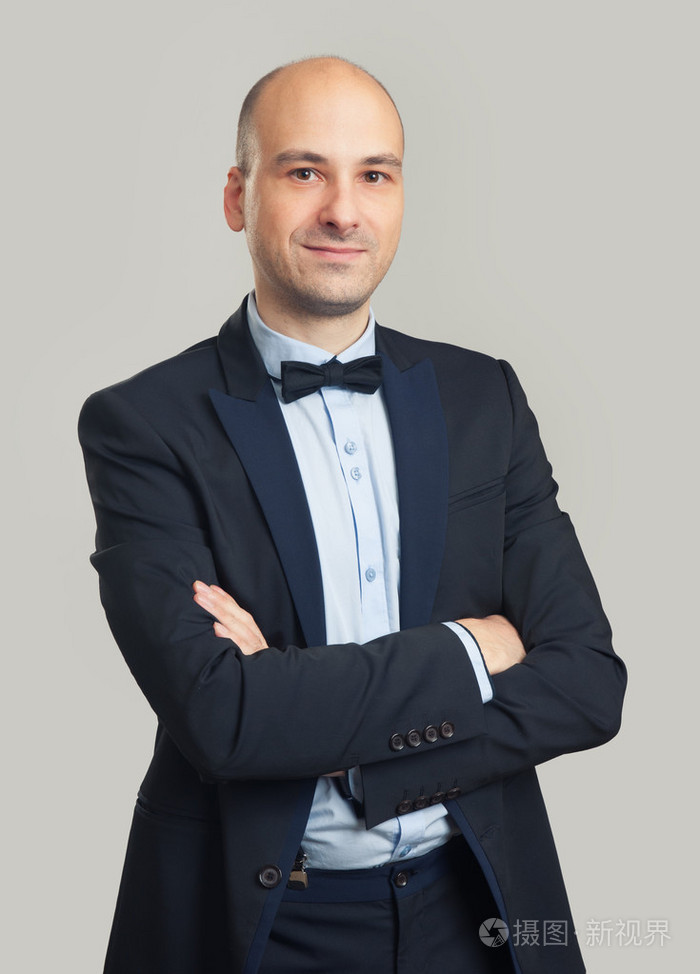 时尚秃头的男人穿着黑色西装和蝴蝶领结