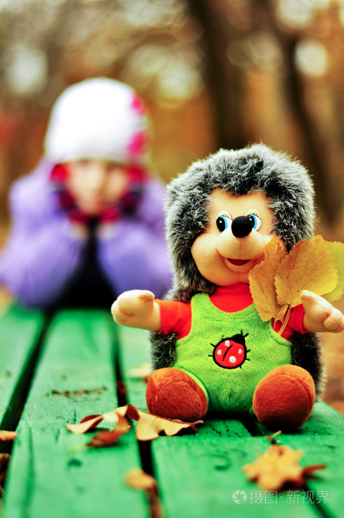 玩具刺猬坐在长椅上的女孩的背景