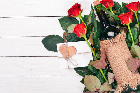一瓶红酒和一束红玫瑰。情人节在木制背景上。顶部视图。文本的可用空间