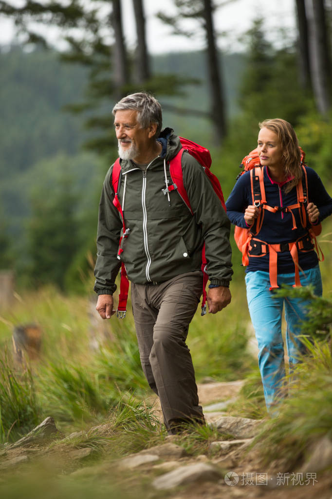 活力的老人和他的女儿在高山徒步旅行