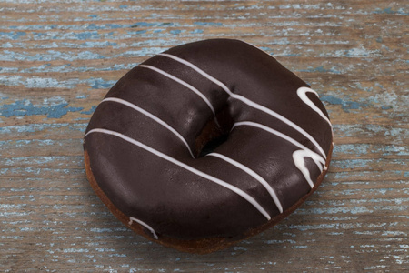木制背景上的白色条纹巧克力甜甜圈