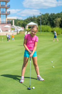 可爱的小女孩打高尔夫球场室外。夏季