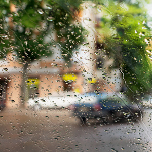 滴的雨水蓝色玻璃背景。街头的散景灯熄灭