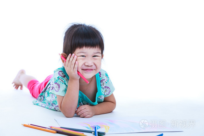 孩子躺在地上画在纸上和微笑。在白色