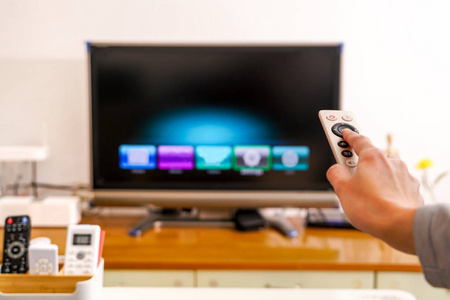 一个妇女手持遥控器的电视盒在客厅里, 黑屏电视