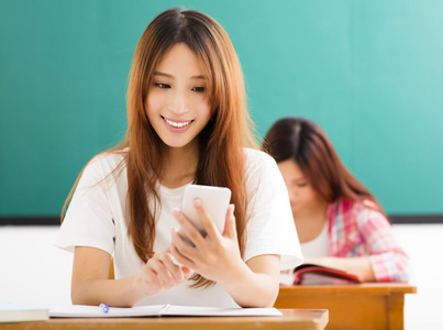 年轻的女学生在教室里使用智能手机