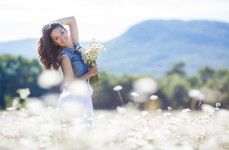 一位年轻女子在草地上捧着一束白色雏菊