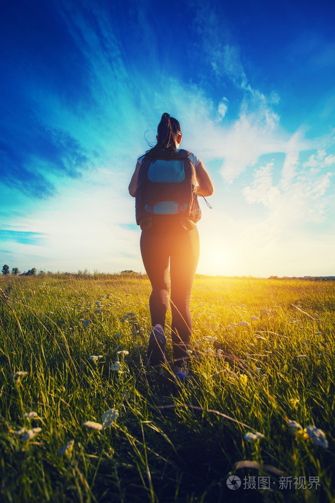 徒步旅行者背包走过一片草地