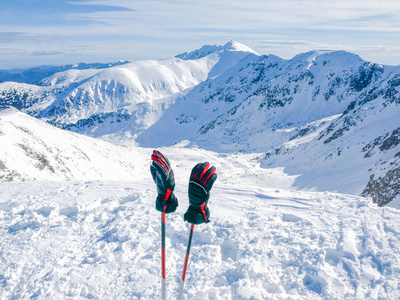 滑雪竿上的冬天山和滑雪手套在前景