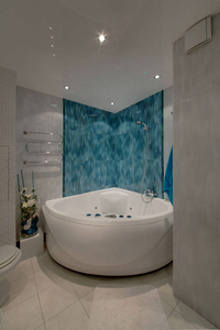 带有蓝色大理石墙地板和墙壁上的轻质瓷砖的按摩浴缸