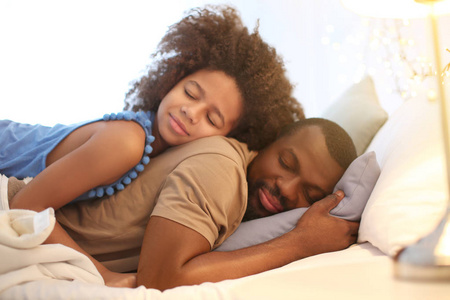 非洲裔美国人和他的女儿睡在床上。家庭就寝时间