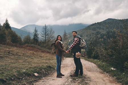 夫妇与背包站立在路在山和牵手