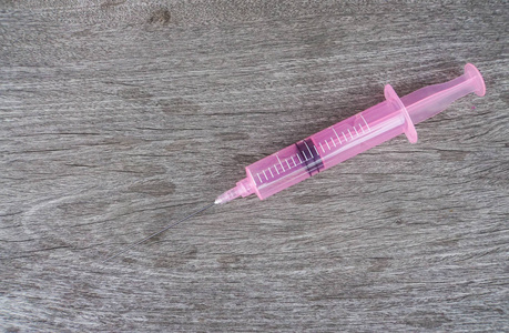 带药的粉红色注射器在病人的木桌上