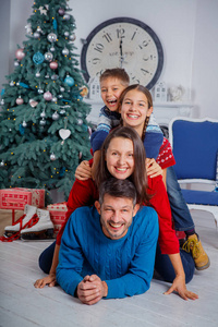 父母和两个可爱的孩子在圣诞树附近玩得很开心