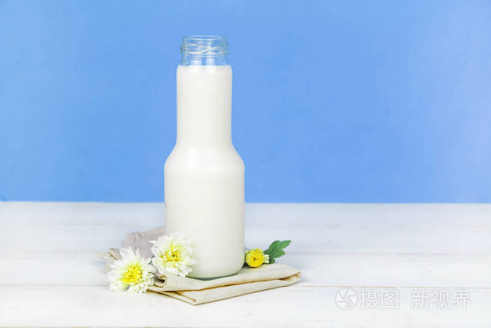 一瓶牛奶和牛奶在背景上木制的桌子上的玻璃
