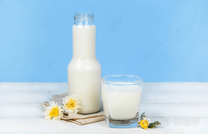 一瓶牛奶和牛奶在背景上木制的桌子上的玻璃照片-正版商用图片0f3a2w