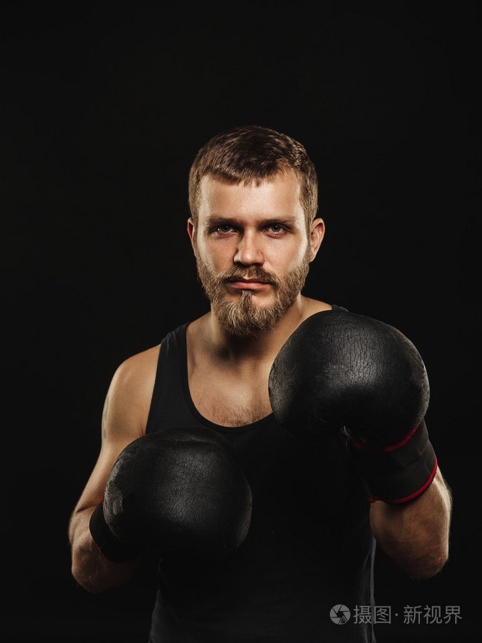 戴着手套在深色背景上的竞技胡子的拳击手