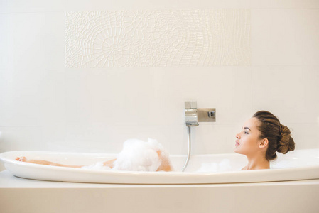 年轻美丽的女人在家里洗澡的侧视图照片