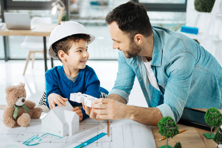 可爱的男孩和他的儿子谈论3d 房子模型