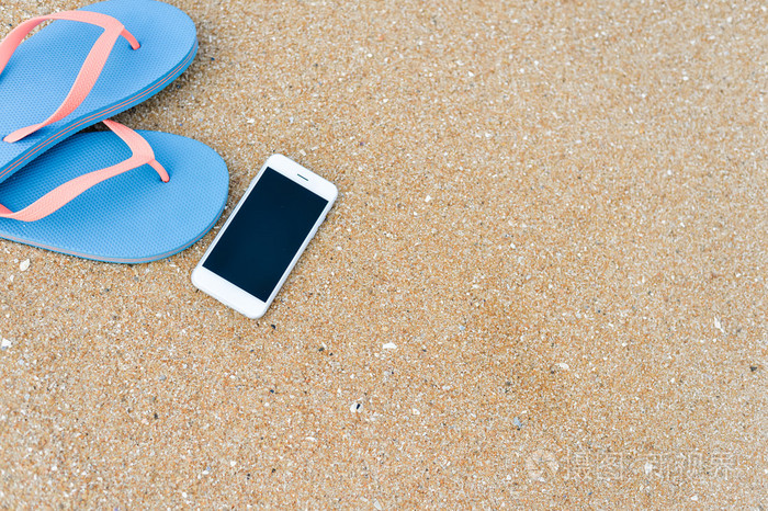 顶视图关闭穿拖鞋夏季海滩背景的移动电话上.愉快的快乐假期