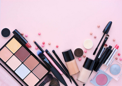 化妆刷和装饰化妆品在柔和的粉红色背景与空白的空间