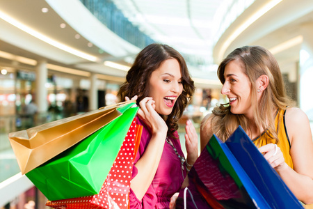 两个女孩在购物中心看着袋购物