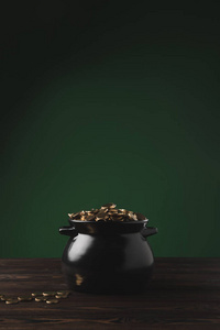 绿色的木桌上的金硬币黑壶, 圣帕特里克日概念