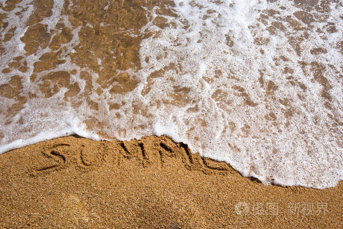 海滩背景与夏天写在沙子中。波和沙子的边界