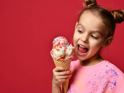 可爱的女孩孩子吃舔大冰淇淋在华夫饼锥体与覆盆子快乐的笑声