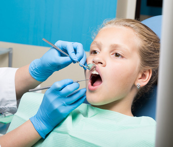 快乐的小女孩接受牙科治疗诊所的嘴巴张开.