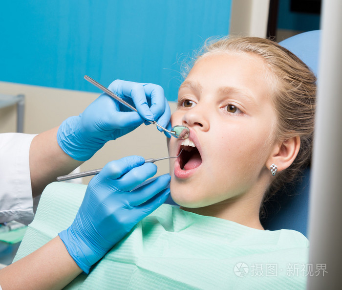 快乐的小女孩接受牙科治疗诊所的嘴巴张开牙医检查和治疗的牙齿在牙科