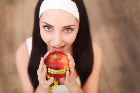 站着红苹果的年轻漂亮微笑的女人。健康食品概念