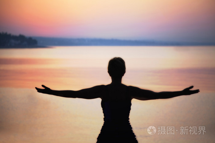 女人深吸一口气在日落时的剪影