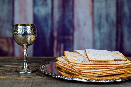 杯逾越节酒和 matzah 特写。背景下的背光模糊 matzah 纹理