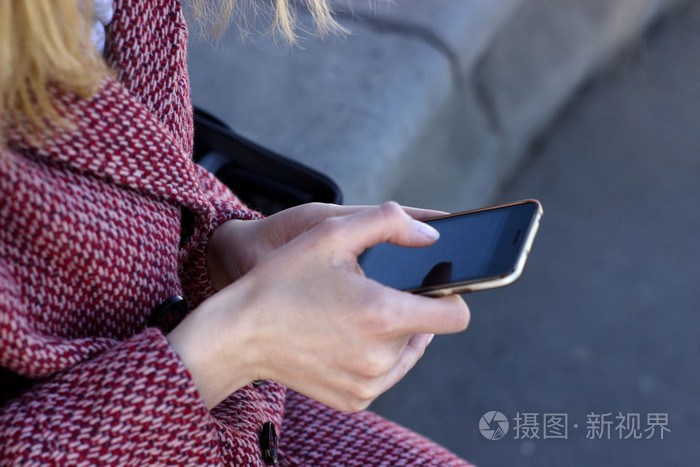 手中用手机和朋友聊天的年轻女人特写